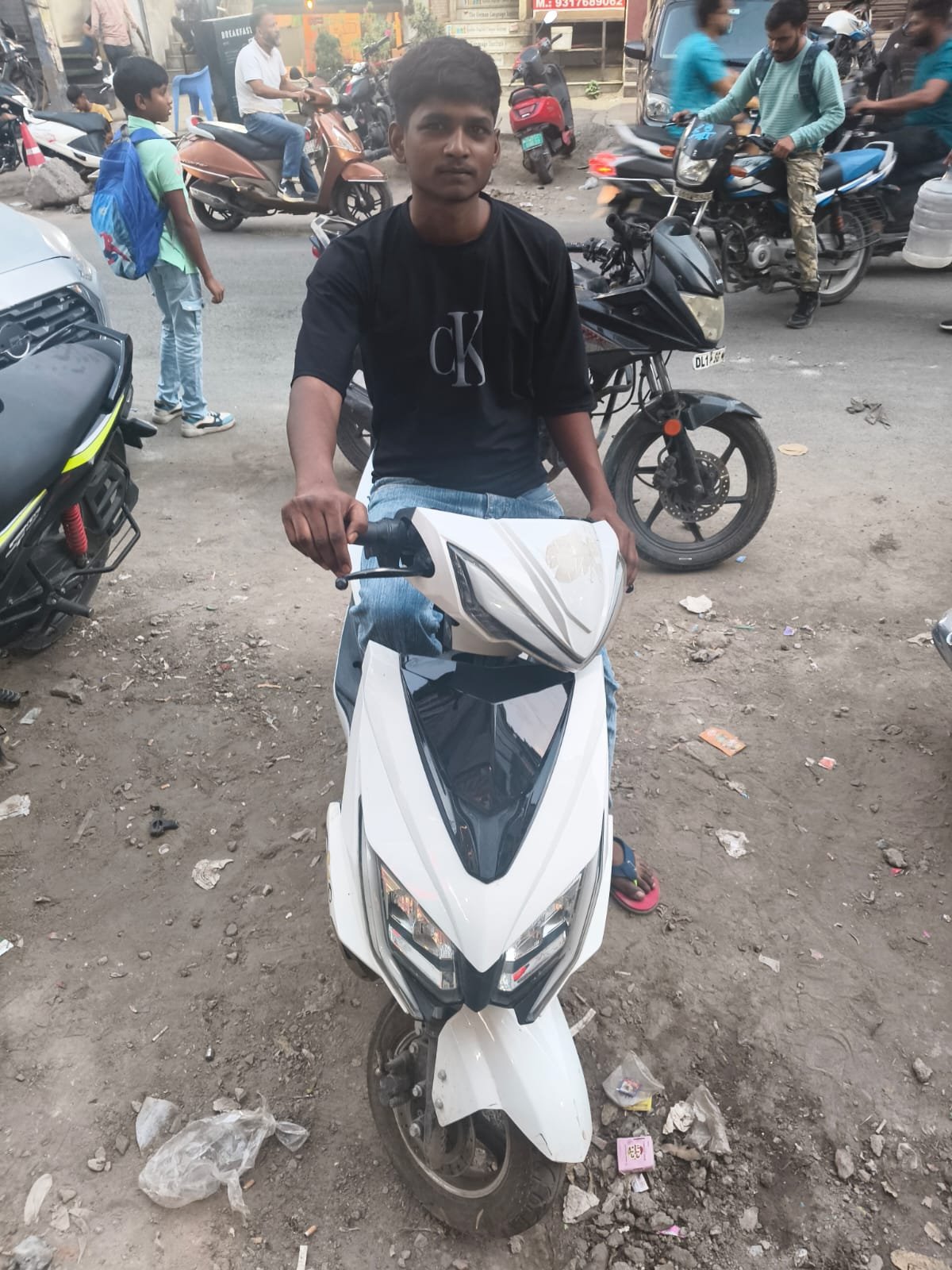 Ozoride rider seated on white electric scooty in market location